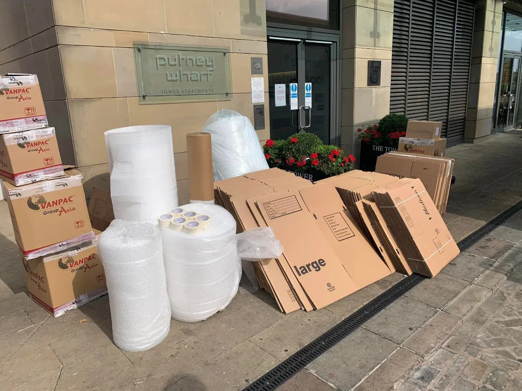 Large boxes being loaded into a van by two employees